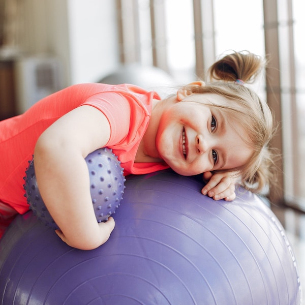 Petite fille avec un ballon en cours de yoga pour enfant